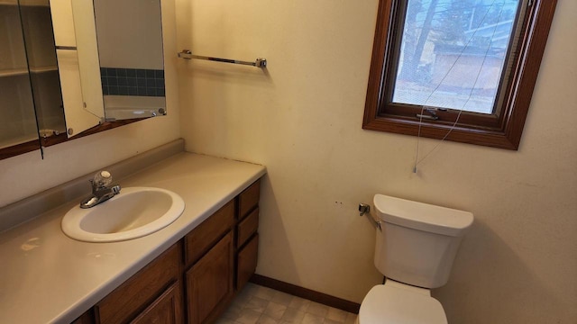 bathroom featuring toilet, vanity, and baseboards