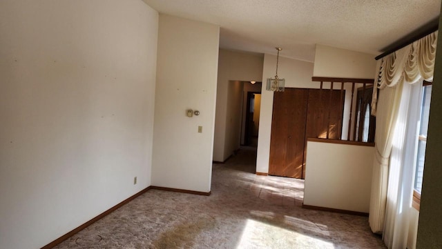 carpeted empty room with a textured ceiling and baseboards