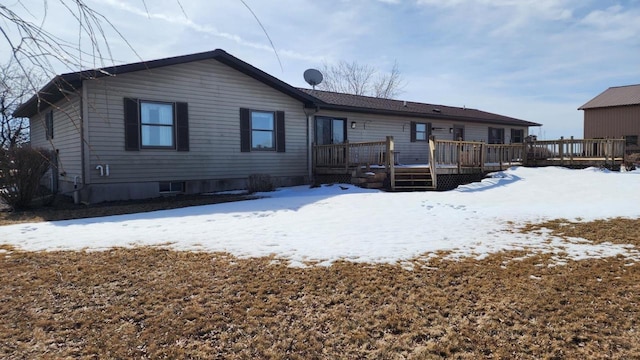 snow covered rear of property with a wooden deck