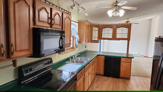 kitchen featuring black appliances, a sink, a baseboard heating unit, light wood-style floors, and a peninsula