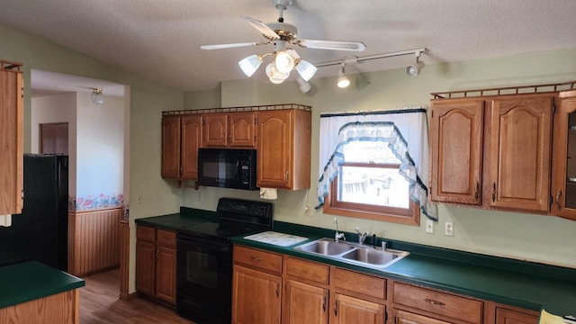 kitchen featuring brown cabinetry, a textured ceiling, black appliances, and a sink