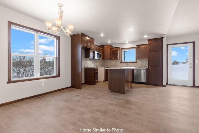 kitchen with a center island, baseboards, light wood-style floors, stainless steel appliances, and a sink