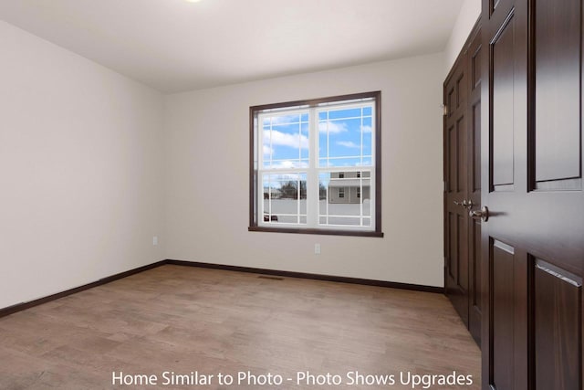 unfurnished room featuring light wood finished floors and baseboards