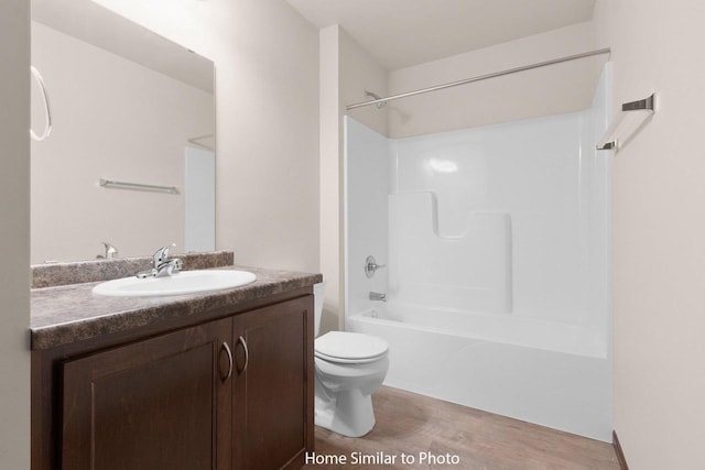 full bath featuring wood finished floors, toilet, vanity, and washtub / shower combination