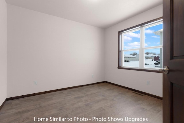 spare room with visible vents, light wood-style floors, and baseboards