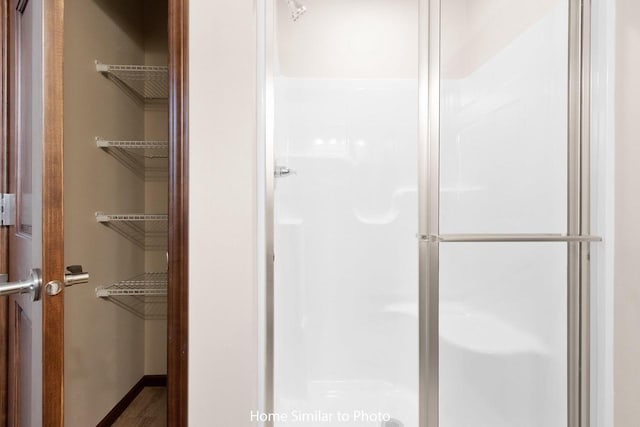 full bath featuring a shower stall and baseboards