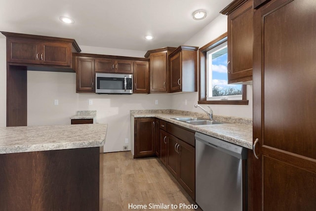 kitchen featuring recessed lighting, a sink, stainless steel appliances, light countertops, and light wood-style floors