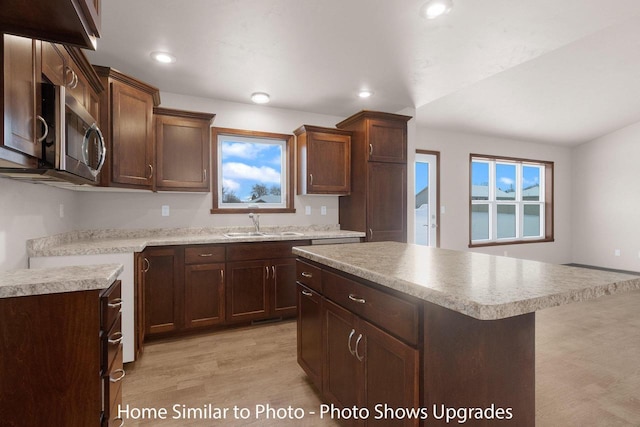 kitchen featuring a sink, stainless steel microwave, recessed lighting, light wood finished floors, and light countertops