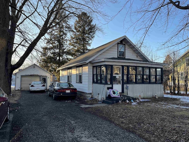 bungalow-style home with an outbuilding, a sunroom, a garage, and driveway