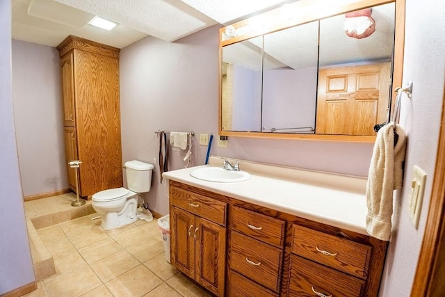 bathroom with vanity, toilet, baseboards, and tile patterned flooring