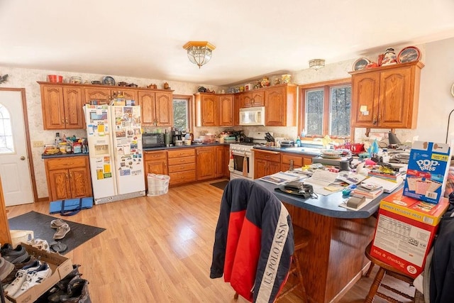 kitchen with brown cabinetry, a healthy amount of sunlight, and white appliances