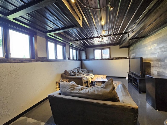 living area featuring a wealth of natural light, finished concrete flooring, and a textured wall