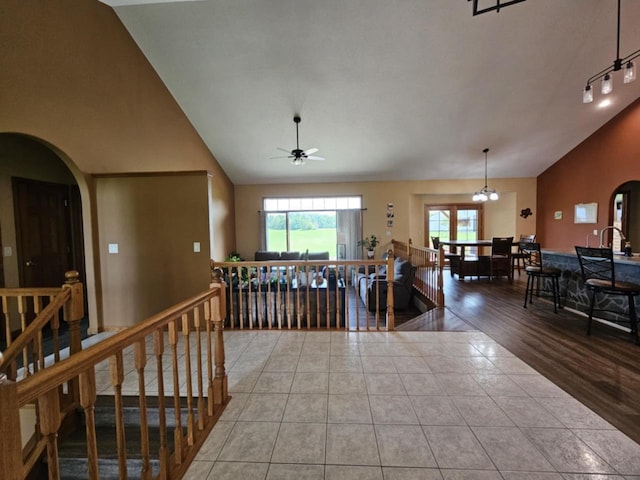 interior space featuring tile patterned floors, an upstairs landing, arched walkways, and high vaulted ceiling