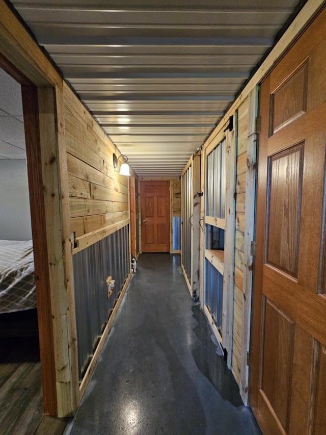 corridor with wooden walls and finished concrete flooring