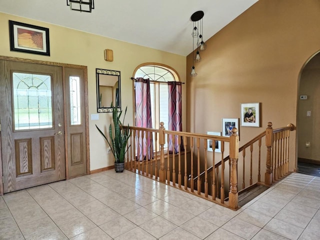 entryway featuring vaulted ceiling, light tile patterned flooring, baseboards, and arched walkways