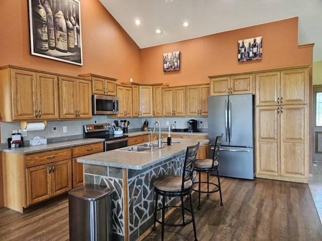 kitchen featuring an island with sink, stainless steel appliances, dark wood-style floors, high vaulted ceiling, and a sink