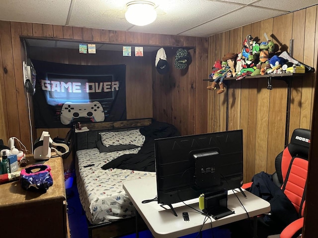 bedroom featuring a drop ceiling and wood walls