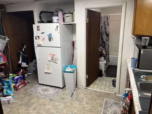 kitchen featuring light floors, freestanding refrigerator, and a sink