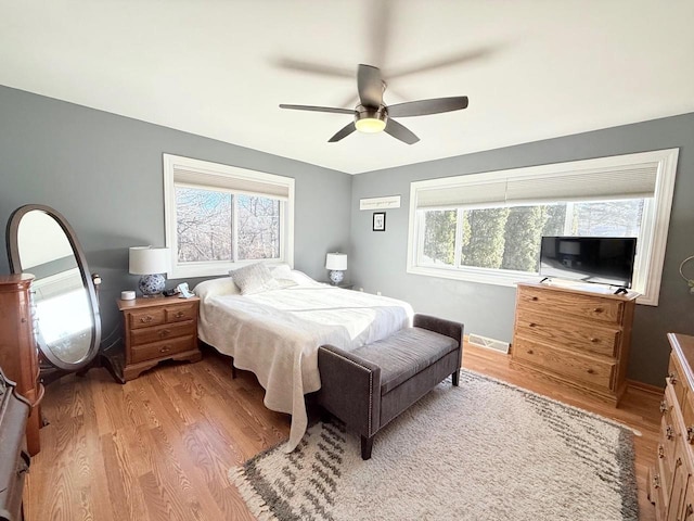 bedroom with a ceiling fan, multiple windows, and light wood-style floors