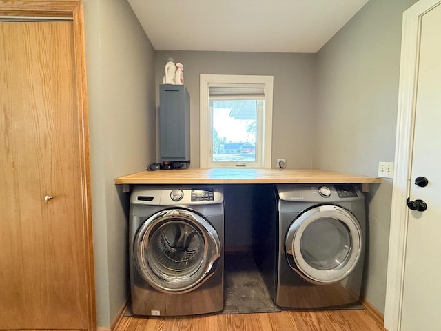 clothes washing area featuring washer and dryer, baseboards, wood finished floors, and laundry area