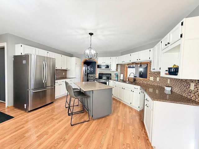 kitchen with a kitchen island, stainless steel appliances, light wood-type flooring, and a sink