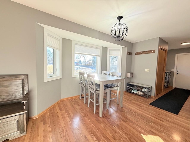 dining area featuring an inviting chandelier, baseboards, and light wood-style floors