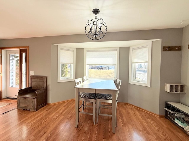 dining area featuring a chandelier, light wood-type flooring, and baseboards