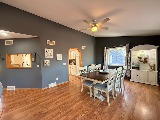 dining space featuring visible vents, arched walkways, and lofted ceiling