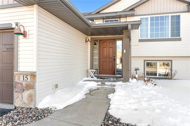 snow covered property entrance with an attached garage