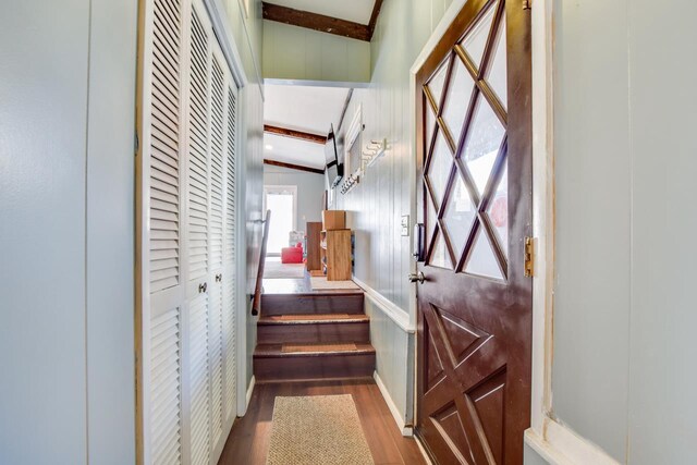 stairway with beam ceiling and wood finished floors