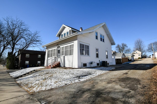 view of home's exterior featuring entry steps, central air condition unit, and a chimney