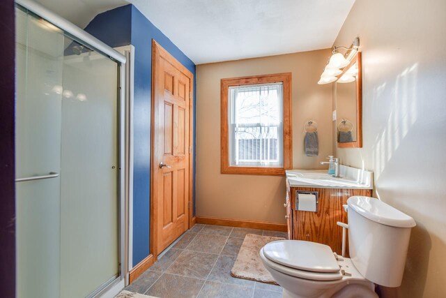 bathroom featuring vanity, a shower stall, toilet, and baseboards