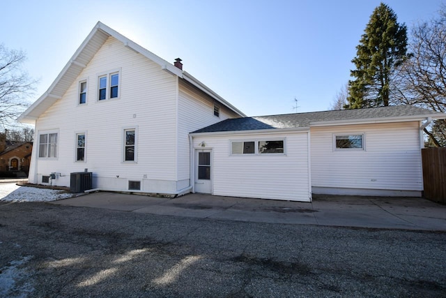 rear view of house featuring a patio, fence, cooling unit, a shingled roof, and a chimney