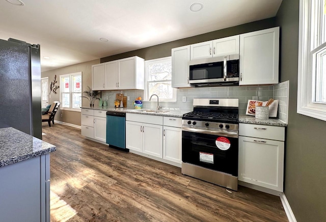 kitchen featuring tasteful backsplash, appliances with stainless steel finishes, dark wood-style floors, white cabinetry, and a sink