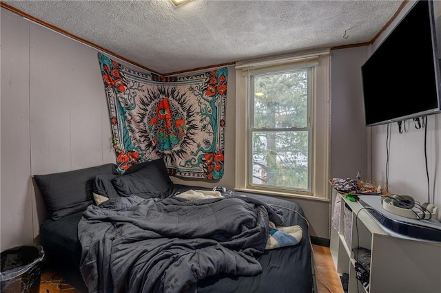 bedroom with a textured ceiling, crown molding, and light wood finished floors