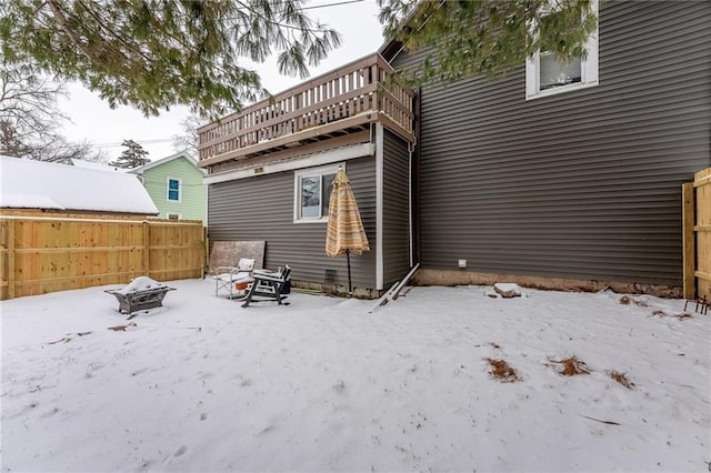 snow covered house with a fire pit and fence