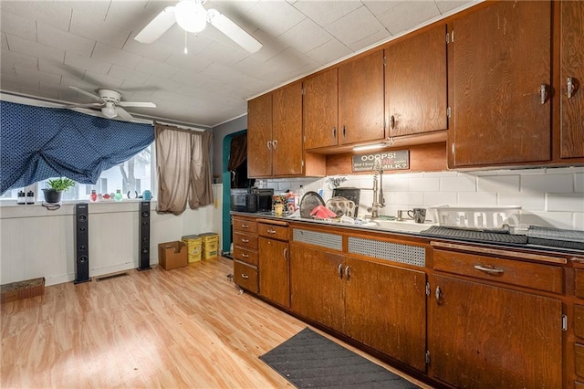 kitchen with light wood finished floors, ceiling fan, dark countertops, and black microwave