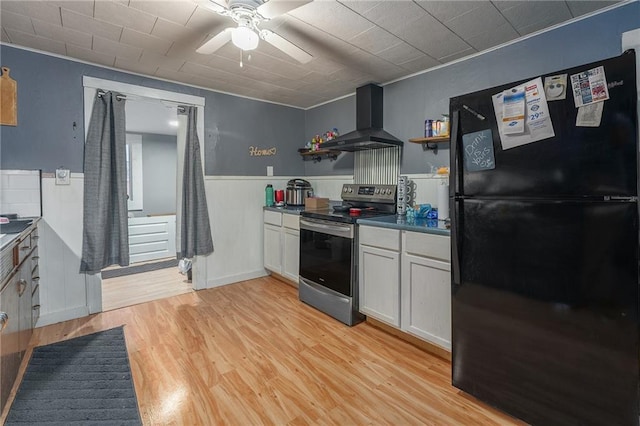 kitchen with extractor fan, stainless steel electric range oven, wainscoting, light wood-style flooring, and freestanding refrigerator