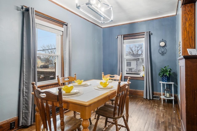 dining area with baseboards, hardwood / wood-style floors, and crown molding