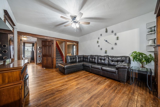 living area with stairs, a ceiling fan, and hardwood / wood-style flooring