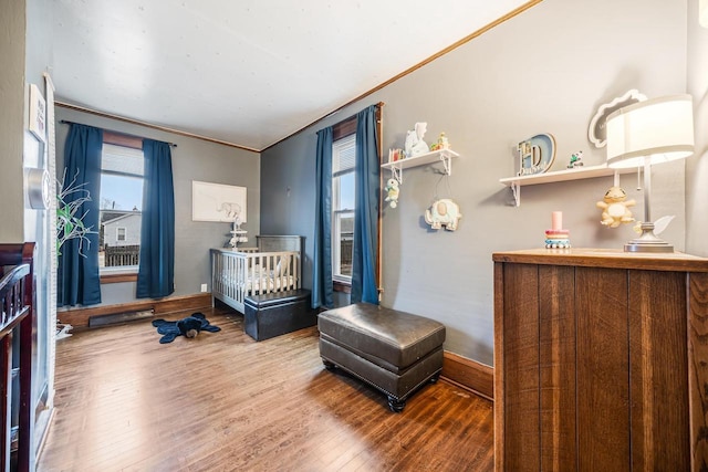 bedroom with ornamental molding, baseboards, and wood finished floors