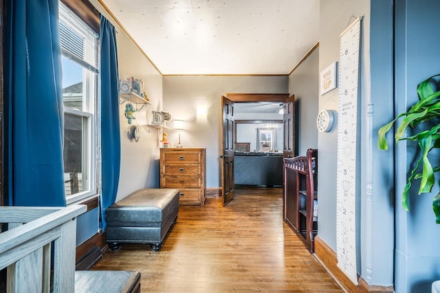 interior space with baseboards, wood finished floors, and crown molding