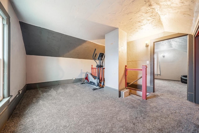 exercise area featuring baseboards, carpet, and lofted ceiling