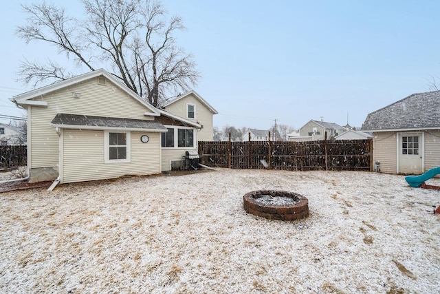 back of house with a fire pit and fence