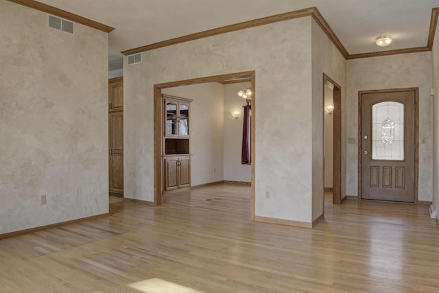 entrance foyer featuring baseboards, visible vents, light wood finished floors, and ornamental molding