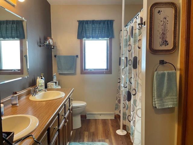 full bath with toilet, plenty of natural light, wood finished floors, and a sink