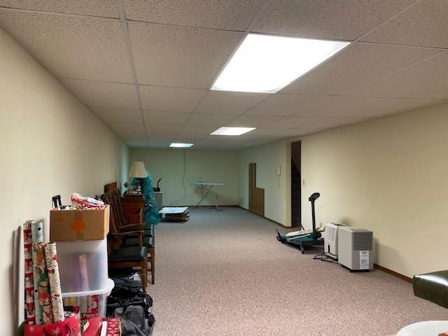 finished basement with a drop ceiling, baseboards, and carpet