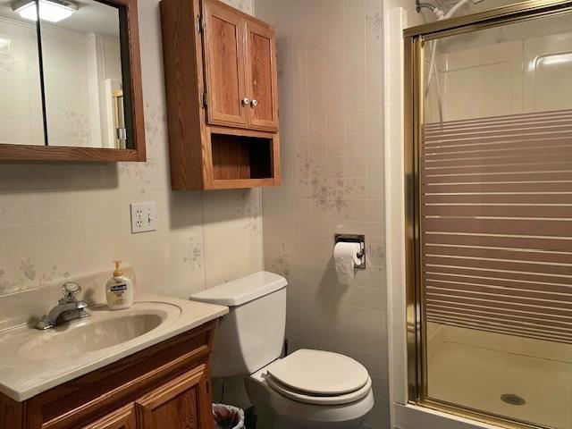 bathroom featuring toilet, a stall shower, tile walls, and radiator heating unit