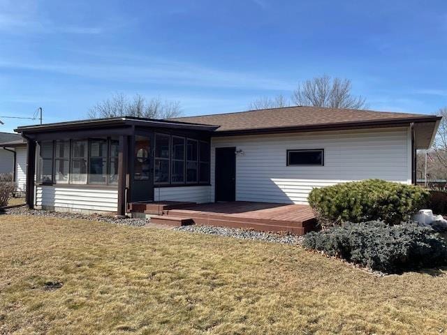 view of front facade with a deck, a front yard, and a sunroom