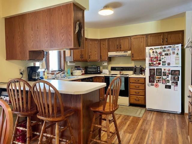 kitchen with extractor fan, light countertops, electric range oven, a peninsula, and freestanding refrigerator